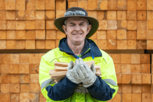 Kurrajong Timber staff holding kindling in his hands while standing in front of stacked bricks